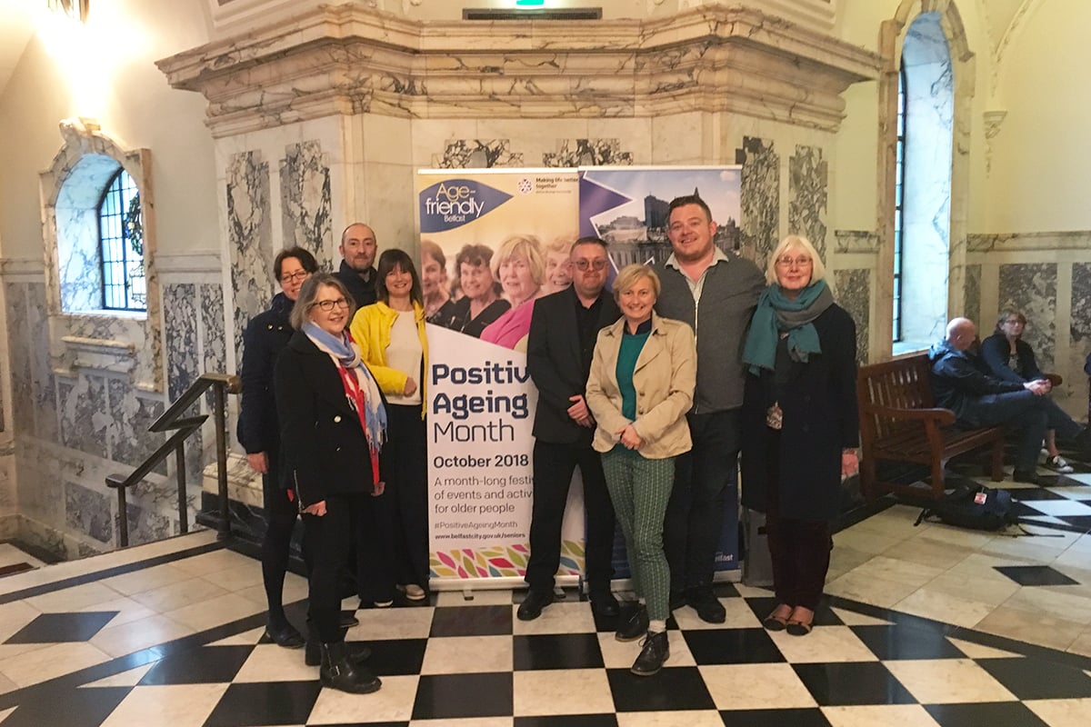 Group of people standing before a Positive Ageing Month banner.