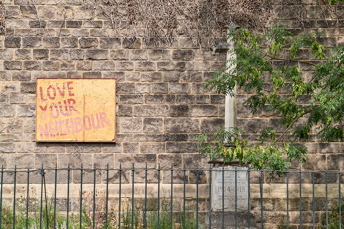 Brick wall with 'love your neighbour' sign.