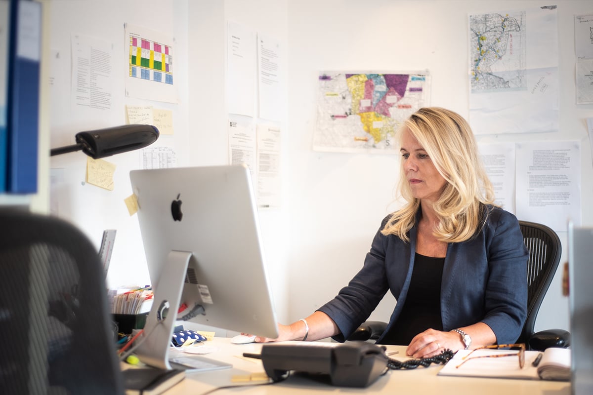 Middle aged woman seated at desk in office.