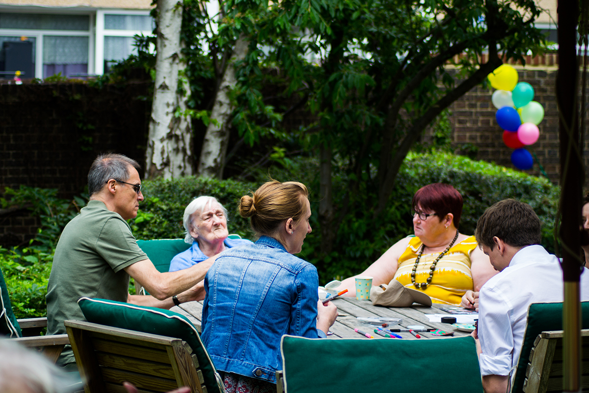 Small group of young and old people sitting at a table on a summer day.