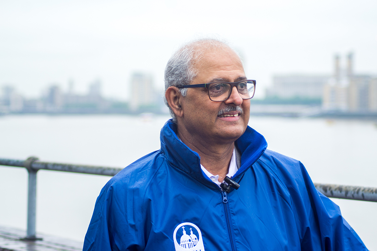 Older Asian man standing in front of the river.
