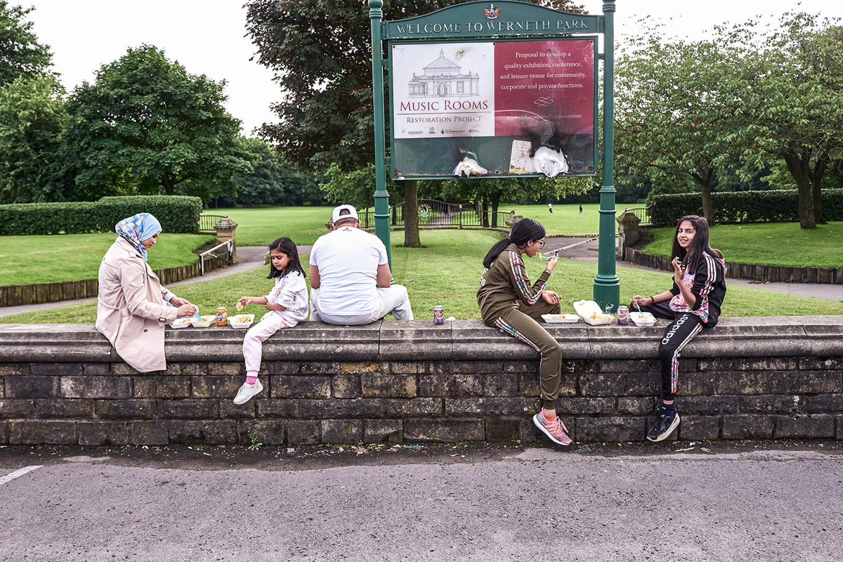 Family group sitting on a wall in a park