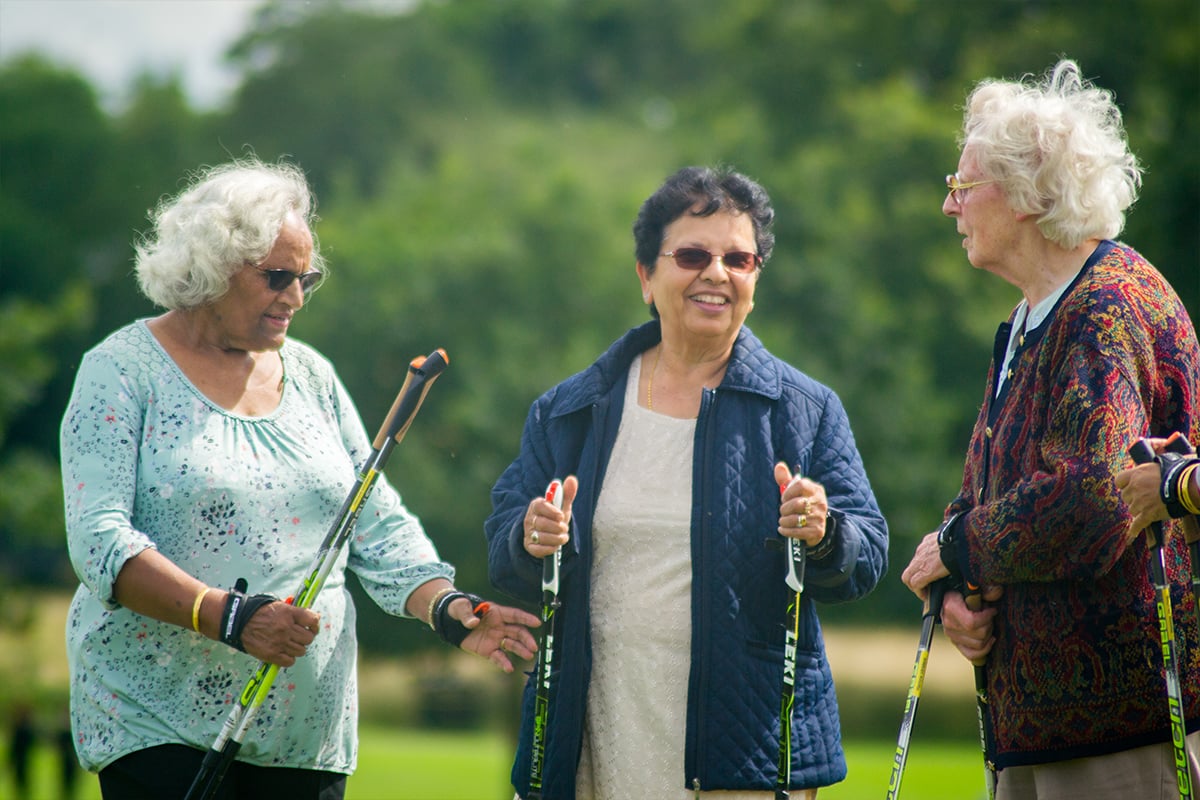 Three elderly women with nordic walking sticks.