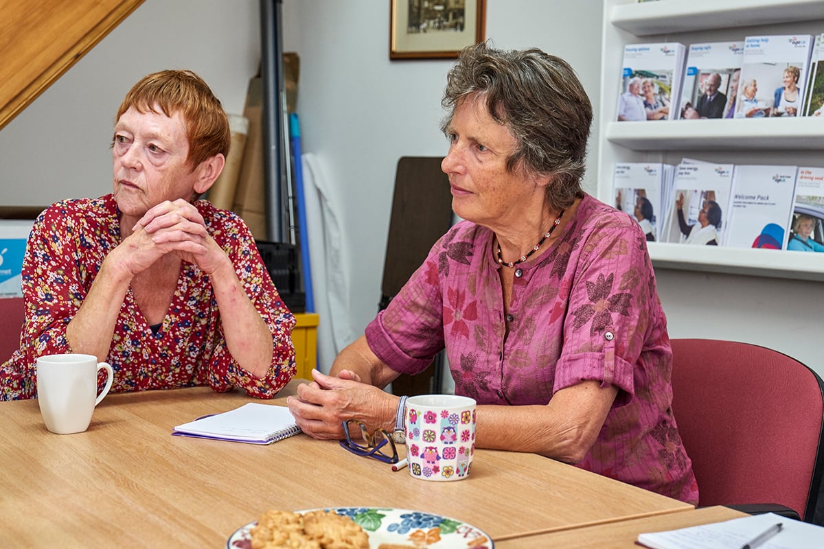 Two older women seated at a table.