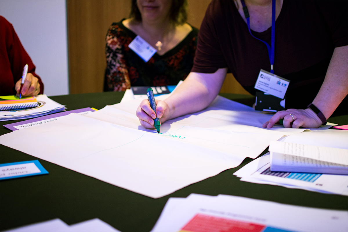 People brainstorming with pens and paper at a conference.