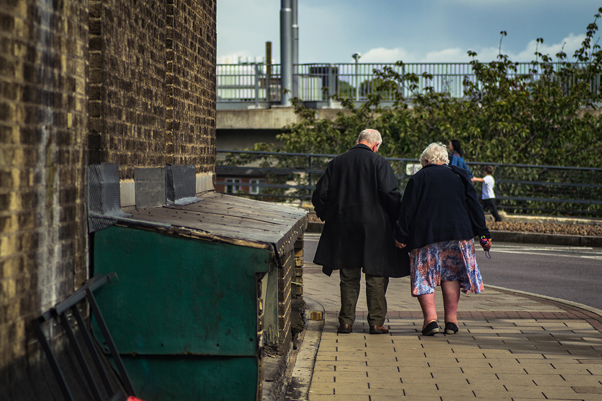 Elderly couple seen walking from behind.
