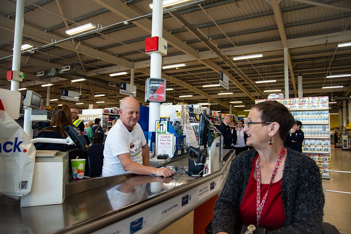 Older worker in supermarket on the till