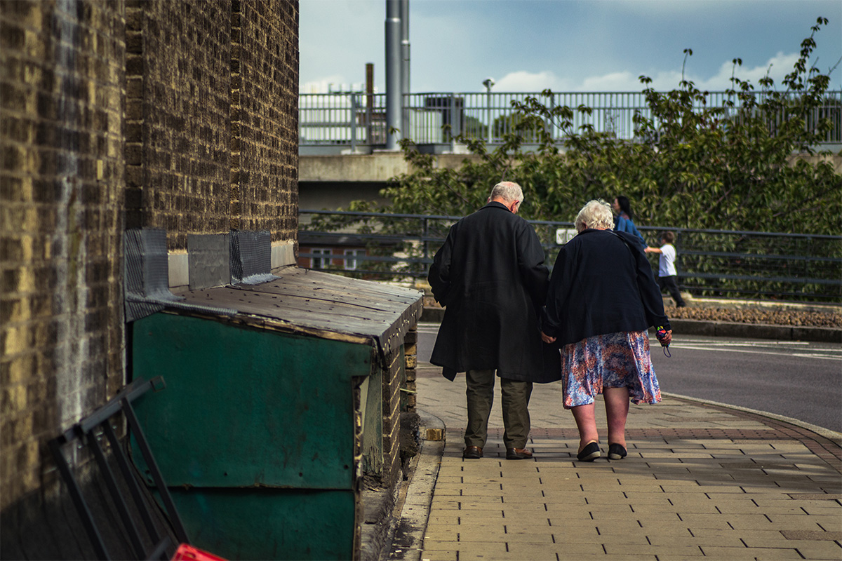 Older man and woman walking down street