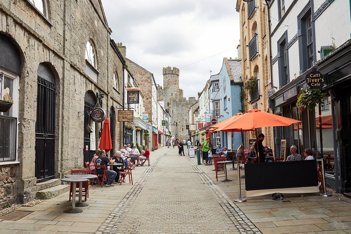 view down a paved street lined with shops and cafes with people seated outside