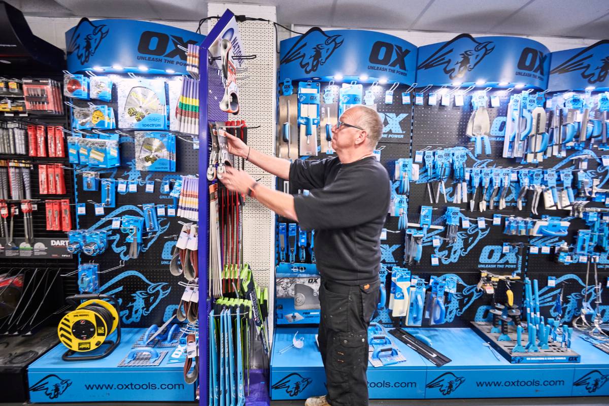 Male worker in a hardware shop tidying stock on the shelves