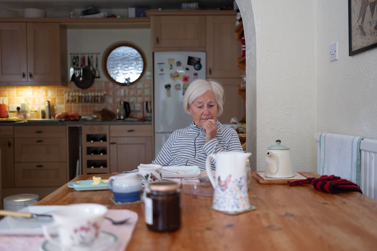 Older woman sitting by a table in her home