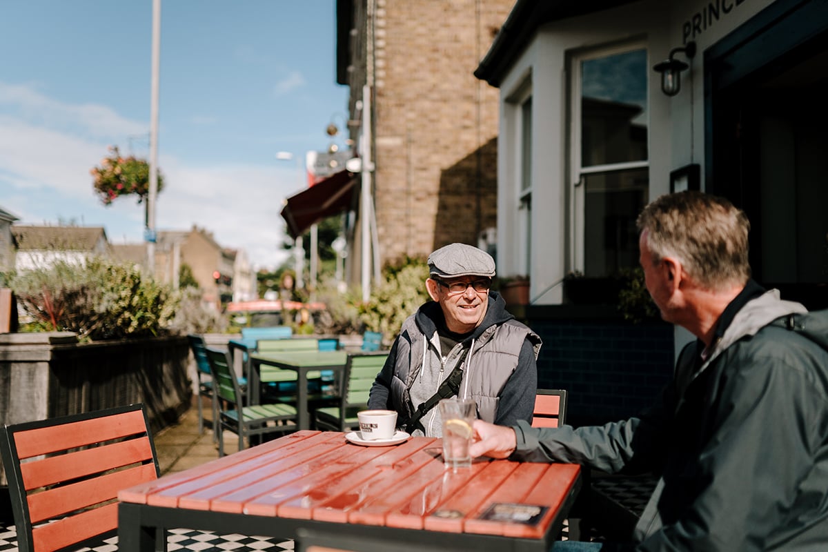 Two older men sitting by a table outside