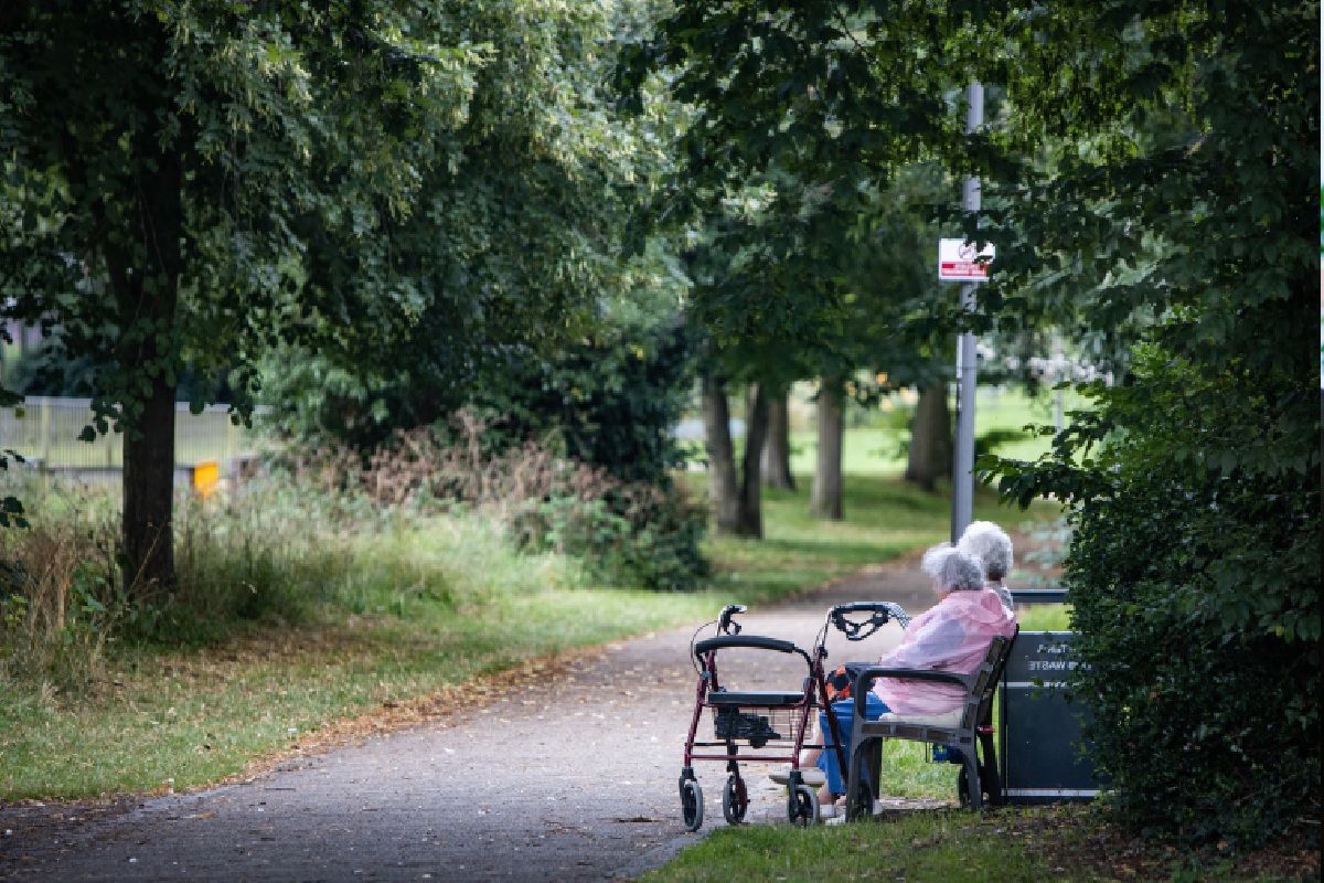 two older people sat on a bench outside