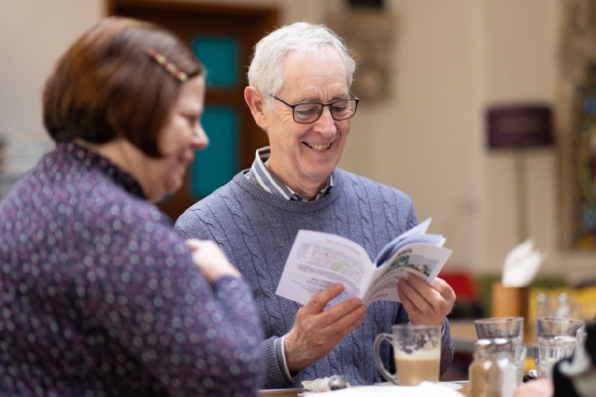 An older man chatting with a woman reading a book