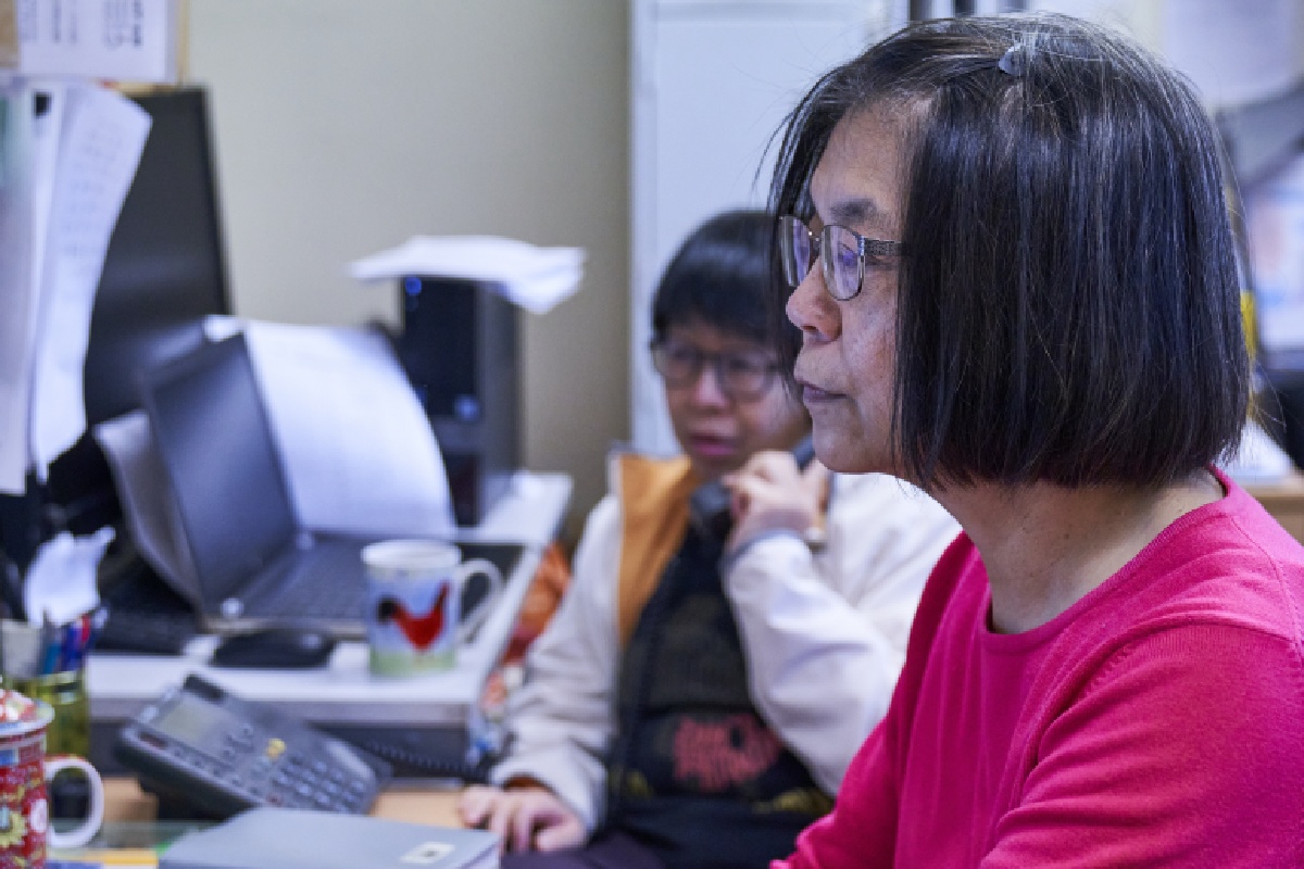 Two women of different ethnicities use computers in an office