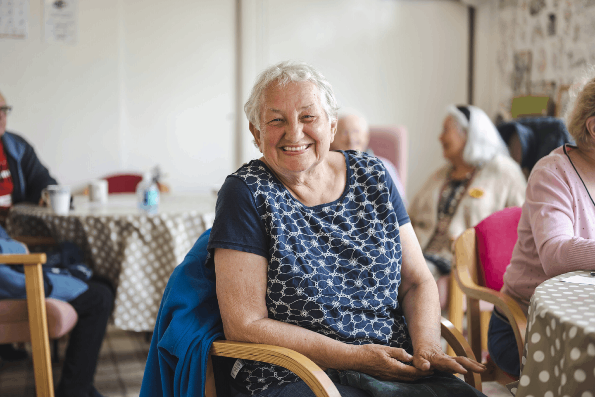 woman in a community hall smiling at the camera