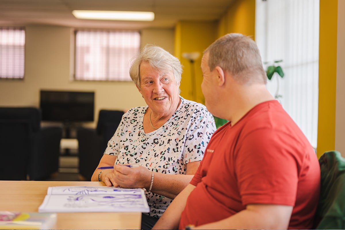 Two older people sitting down and chatting