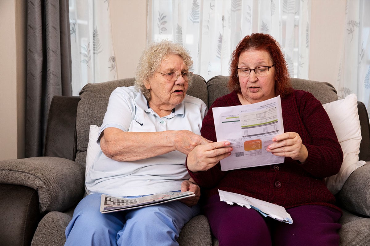 Two older women reading bills