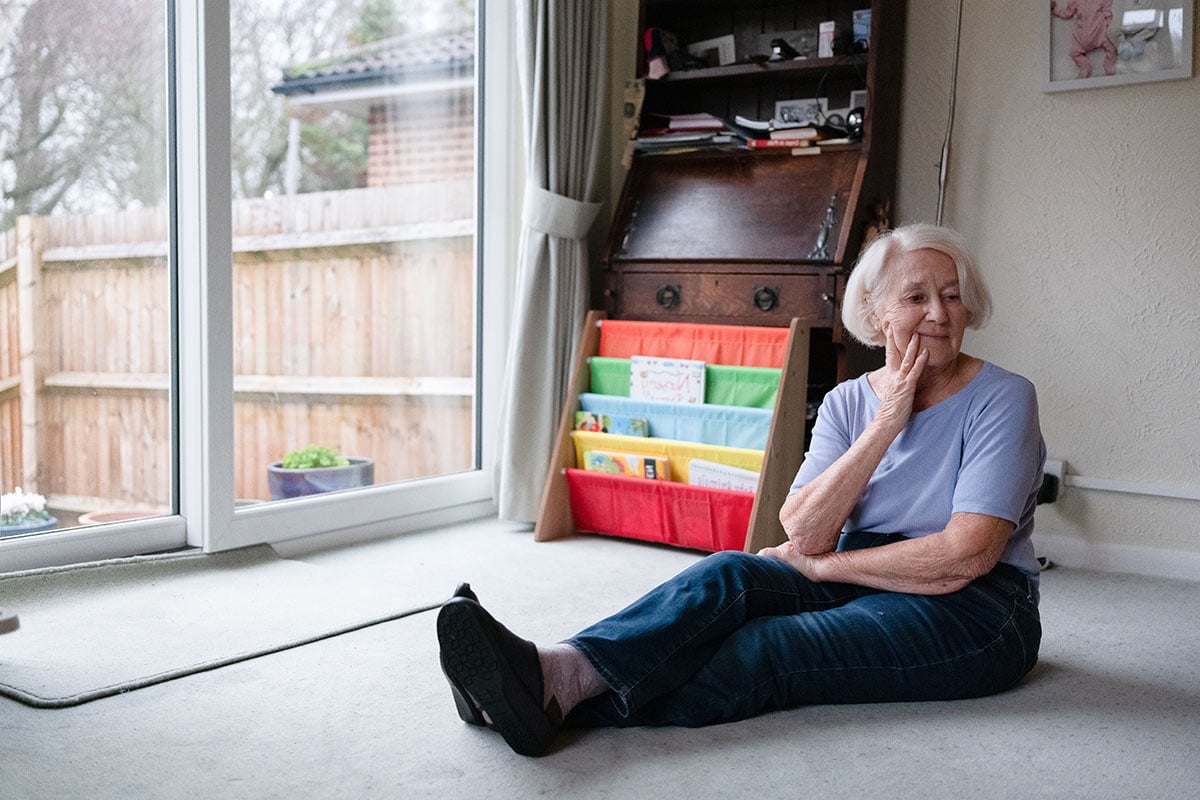 Older woman sitting on floor in her home