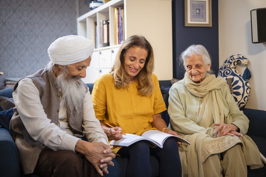 A Sikh family sitting on their sofa making planning notes in a notebook