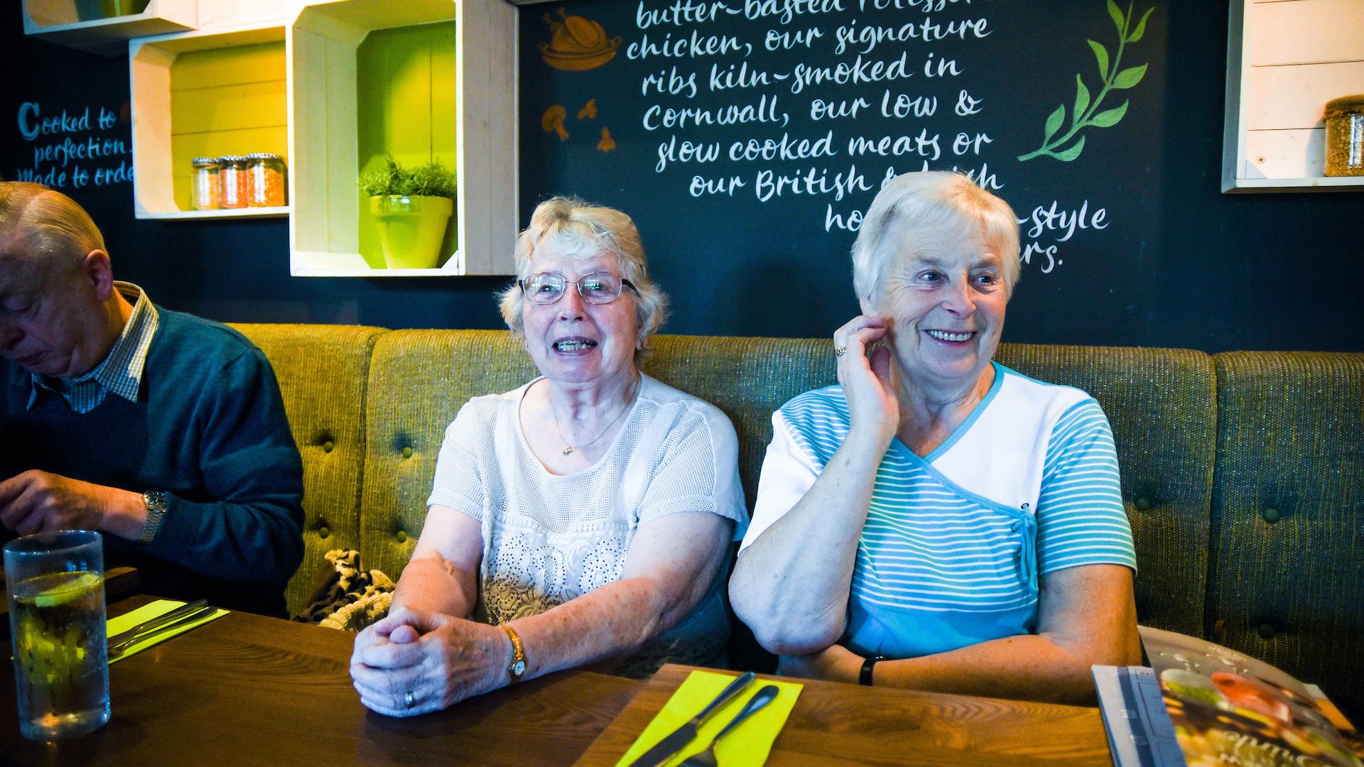 Two older ladies at a table sharing a laugh