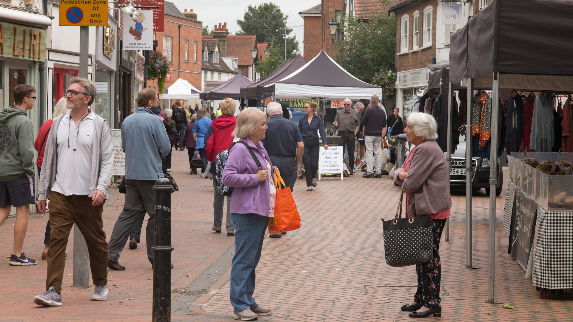 View of shoppers at a street market. Two older women having a conversation