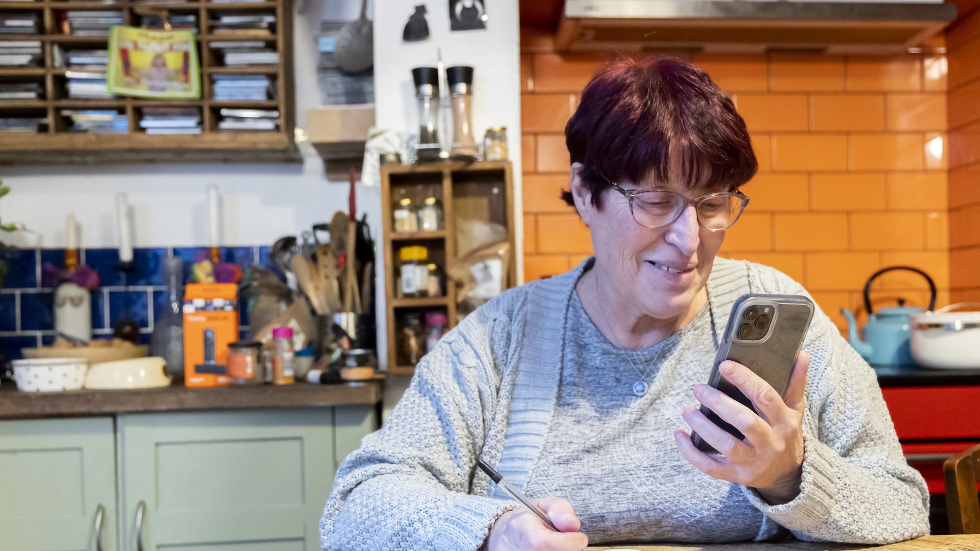 Older woman using phone in kitchen