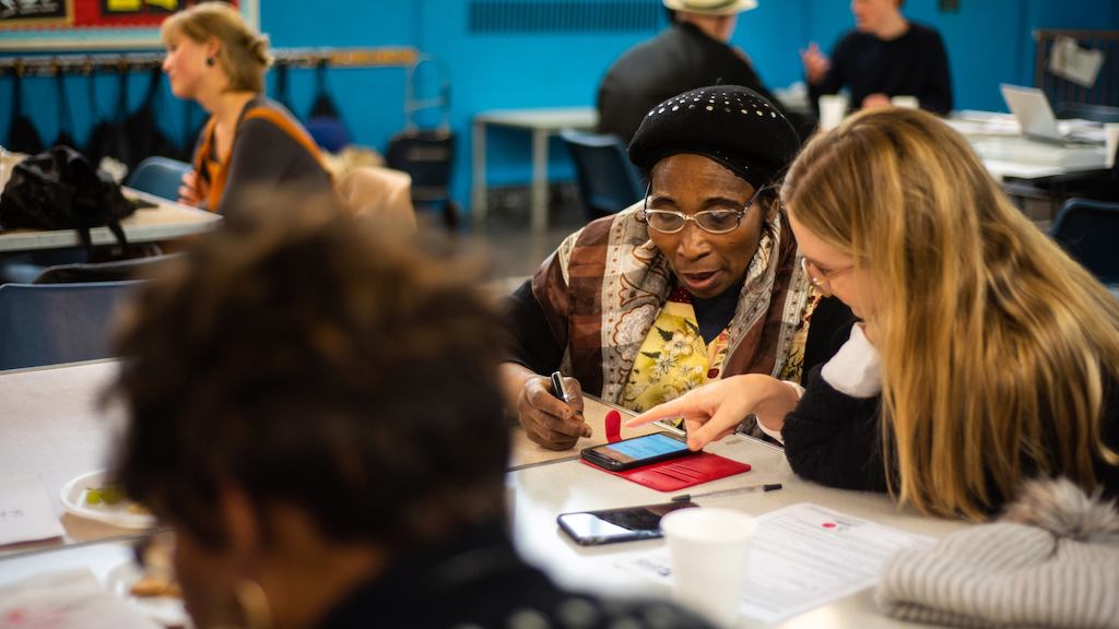 Older and younger person using phone at South London Cares workshop