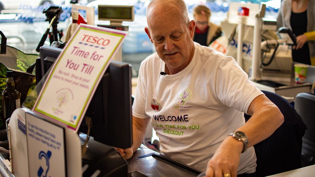 Man working at Tesco till.