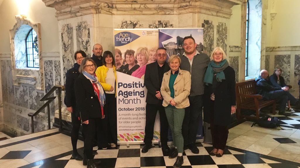Group of people standing before a Positive Ageing Month banner.