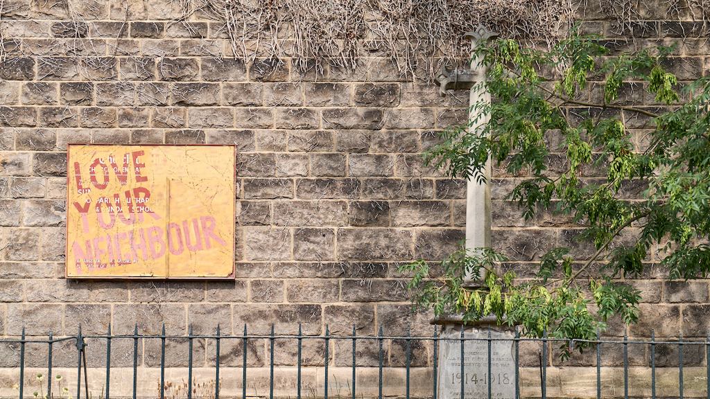 Brick wall with 'love your neighbour' sign.