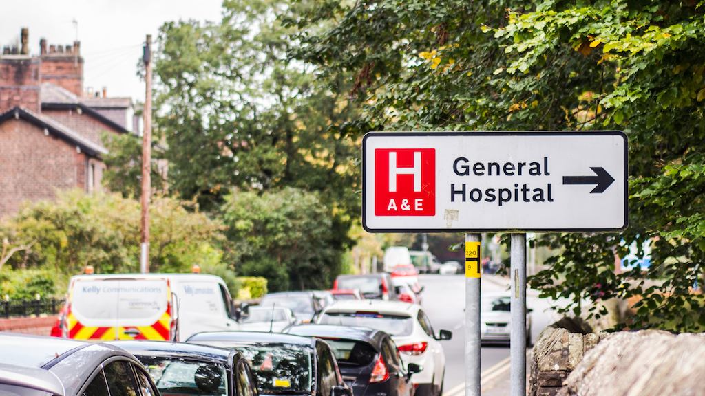 This photo is taken on the street outside of a hospital with sign saying 'General Hospital'.