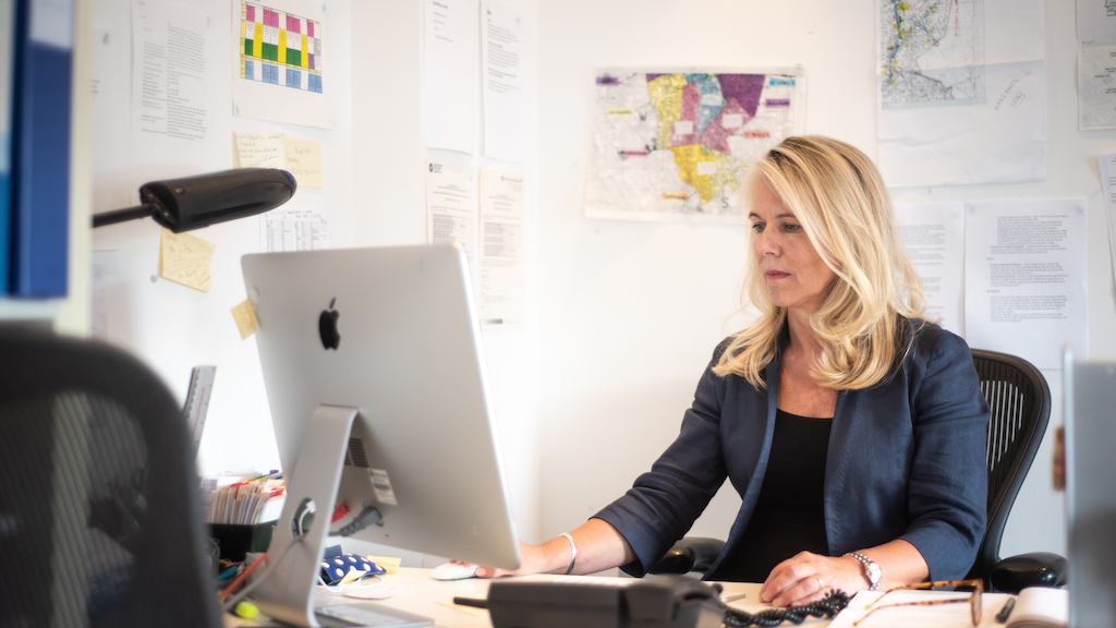 Middle aged woman seated at desk in office.