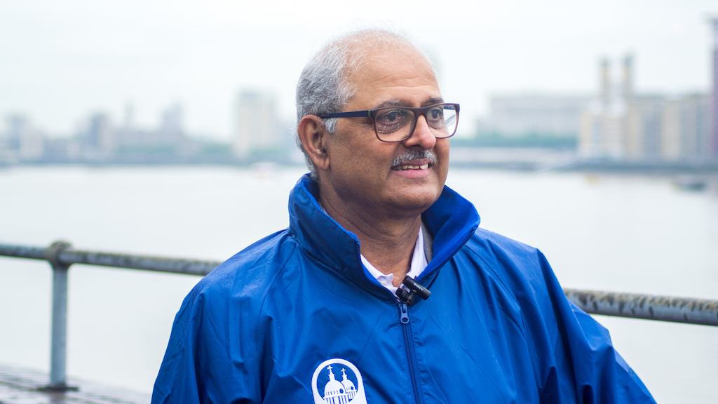 Older Asian man standing in front of the river.