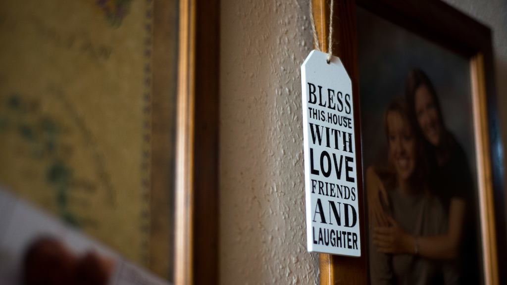 'Bless this house with love, friends and laughter' tag hanging from a family photo.