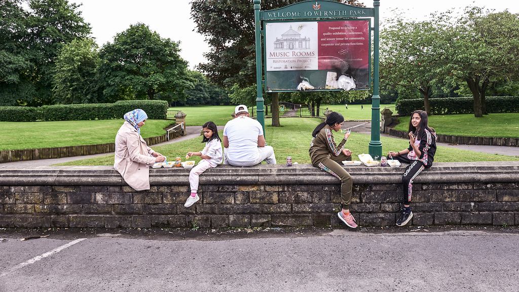 Family group sitting on a wall in a park
