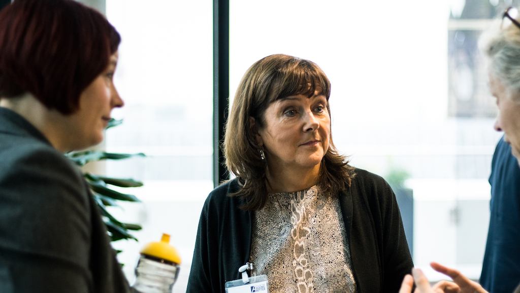 Three older women in a discussion during conference break.