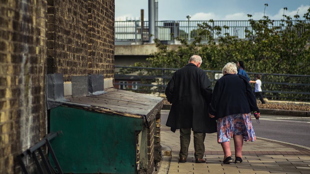 Elderly couple seen walking from behind.