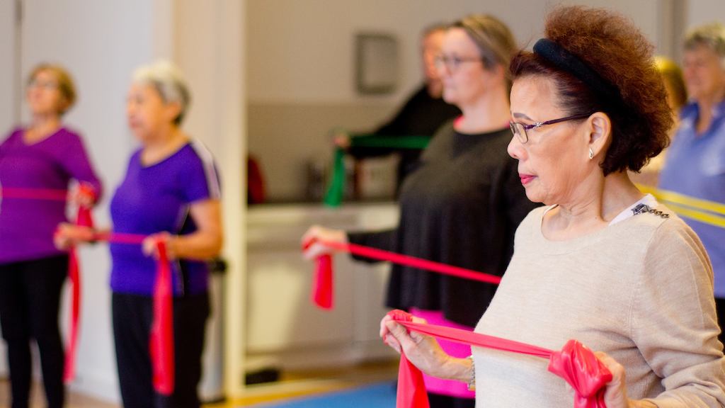 Older Asian woman using resistance band