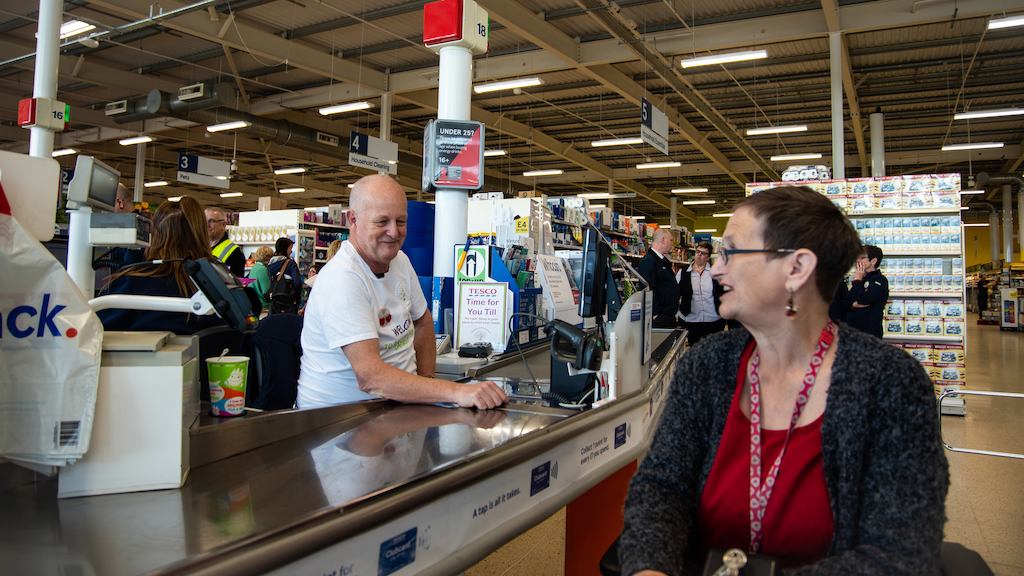 Older worker in supermarket on the till