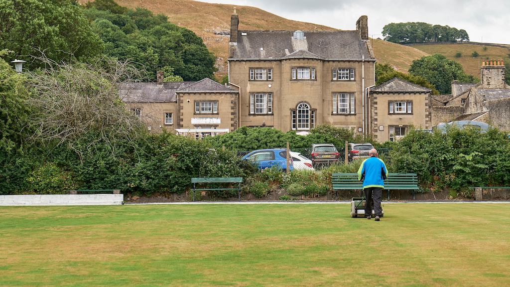 Landscape of hill and older man mowing grass