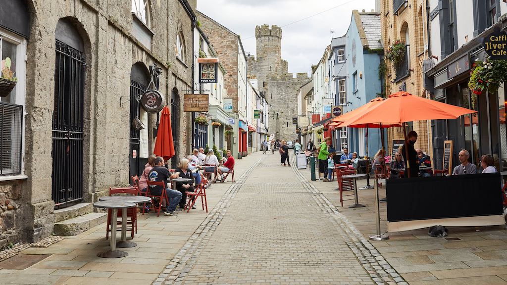 view down a paved street lined with shops and cafes with people seated outside