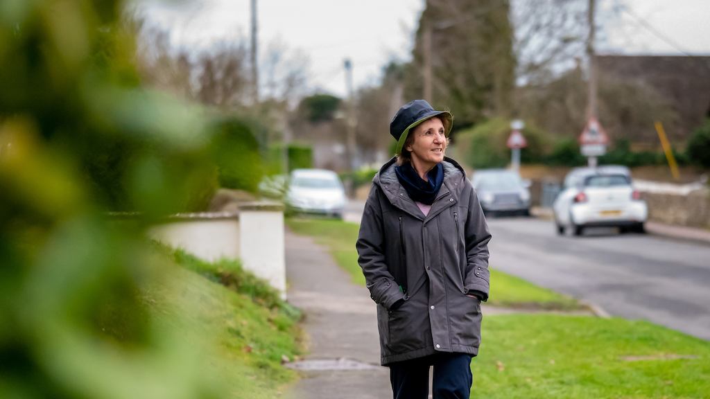 an older woman walking along a residential street
