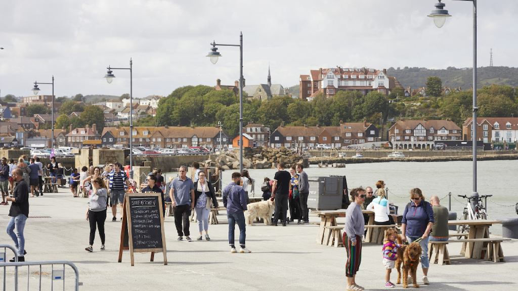 view of a sunny seaside pier with people enjoying the sunshine