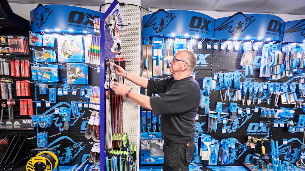 Male worker in a hardware shop tidying stock on the shelves