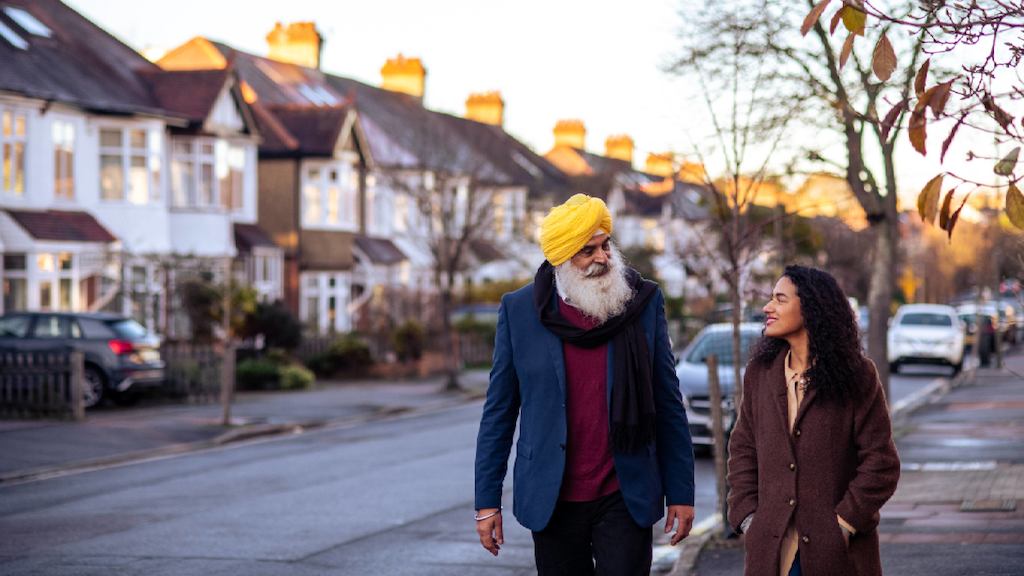 Older man and younger woman walking on street together