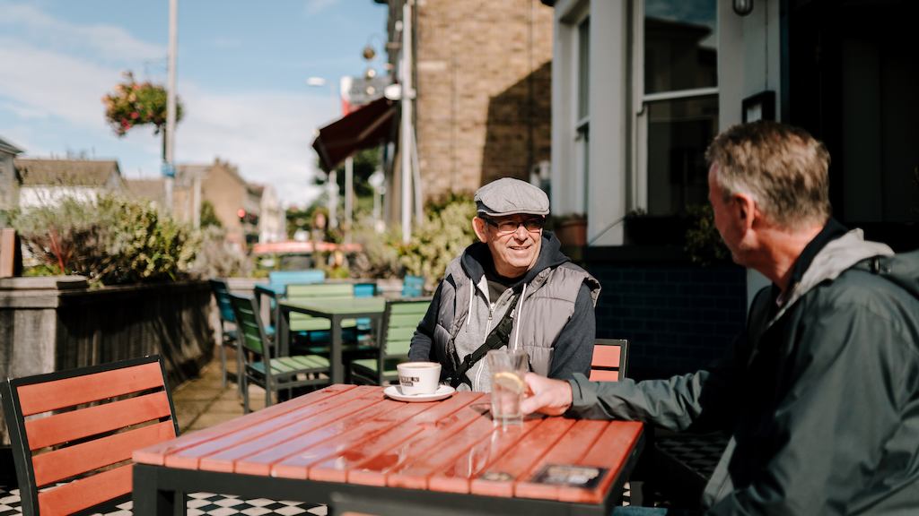 Two older men sitting by a table outside