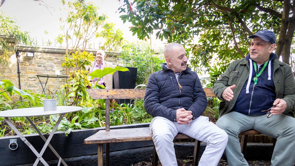 two men sitting outside talking
