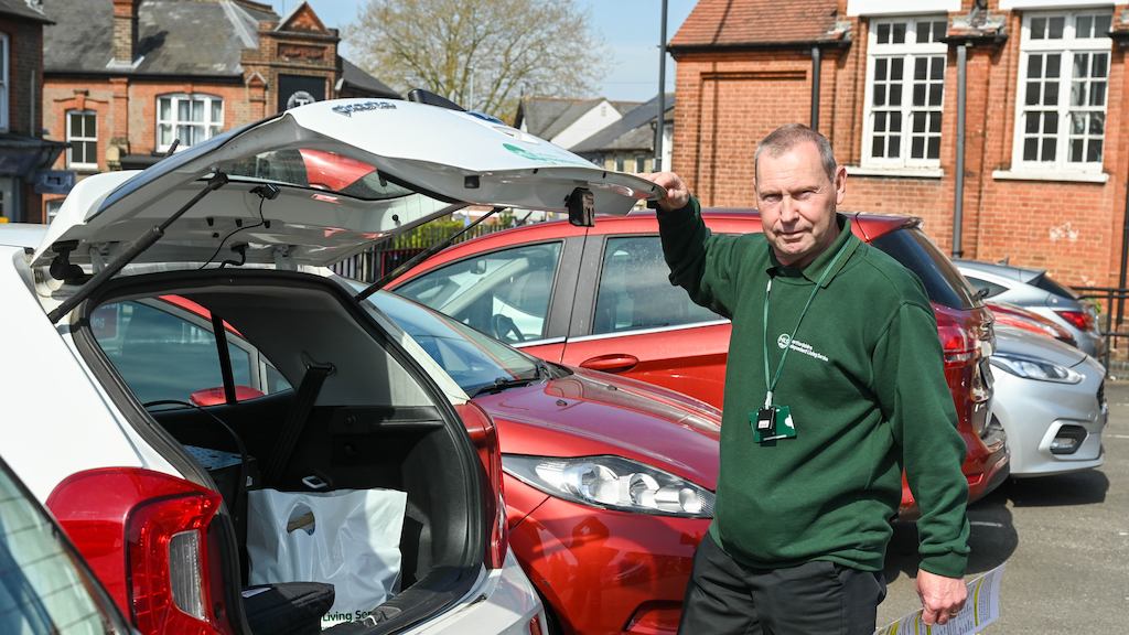 Older worker standing by car