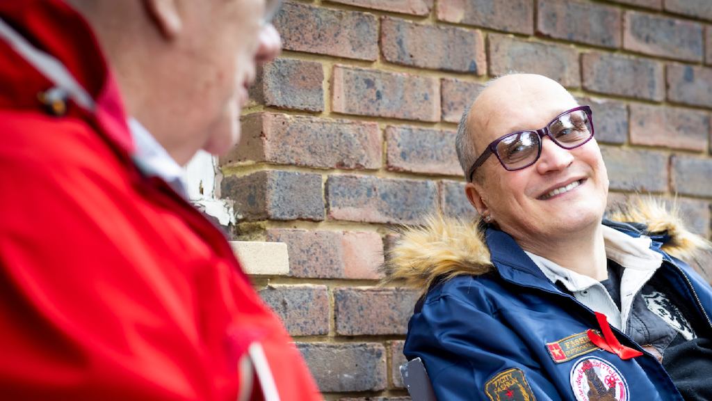 two men sitting outside talking